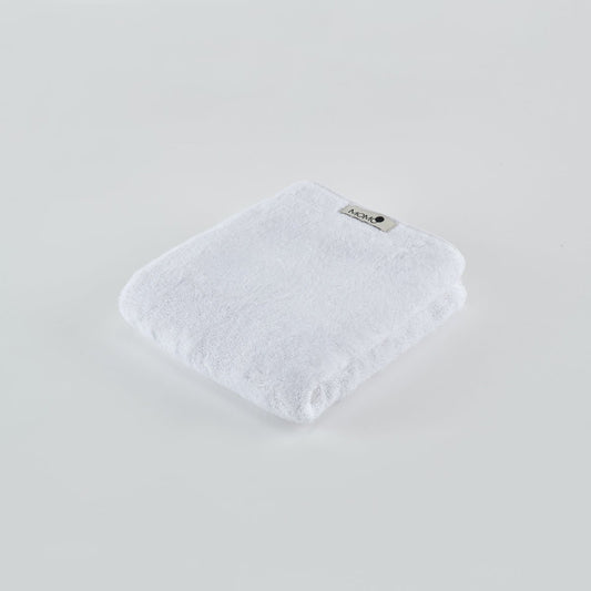 Serviette en bambou blanc Momo Cotton pliée sur fond clair avec étiquette de marque visible