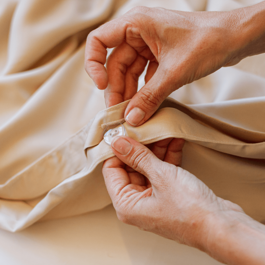 Hands touching soft beige cotton bedding and towels from Momo Cotton complete linen set