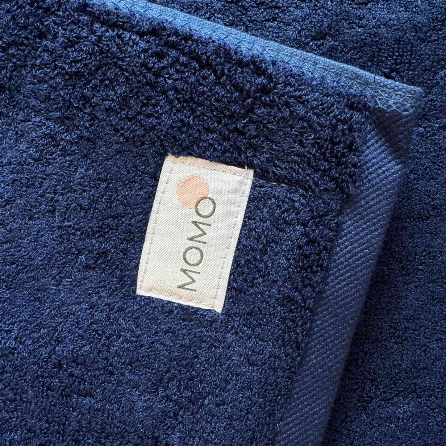 Tapis de bain bleu marine Wabi-sabi Momo Cotton avec étiquette de marque visible sur tissu texturé