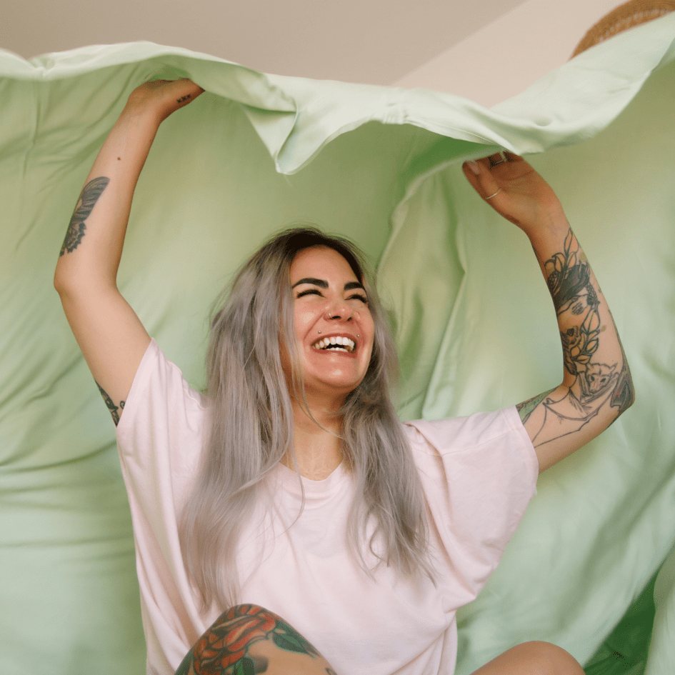 Smiling woman holding green and white bedding for comfortable summer nights