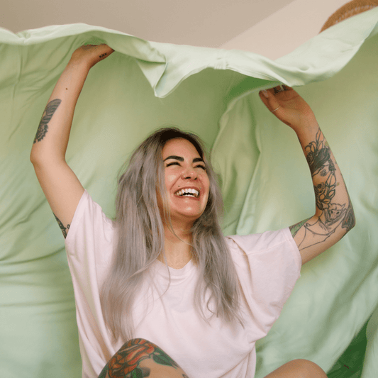 Smiling woman holding green and white bedding for comfortable summer nights