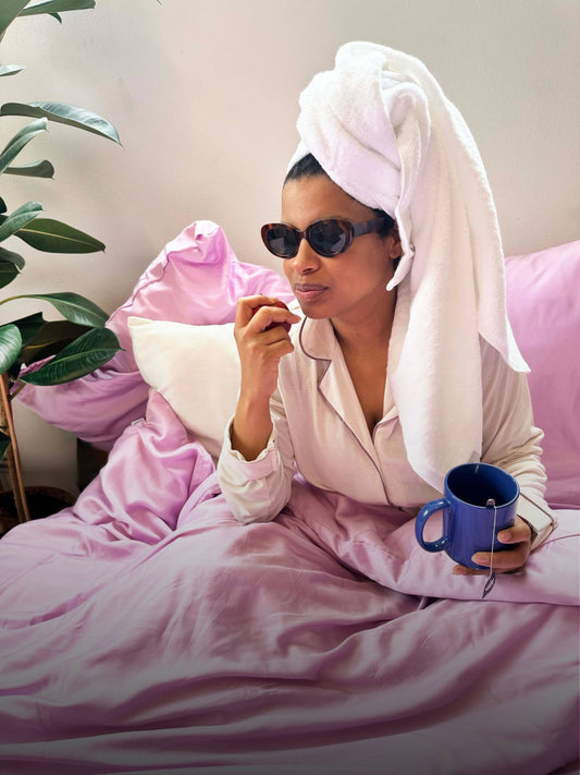 Towels in bed with stylish woman enjoying tea