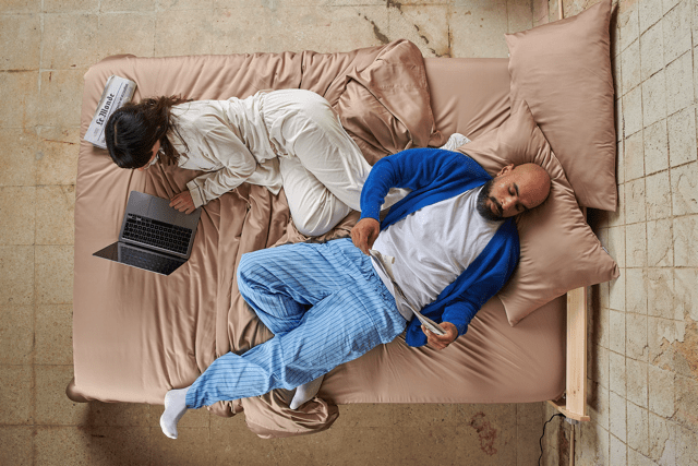 Couple au lit avec draps en bambou pendant la journée, montrant le confort toute l'année.