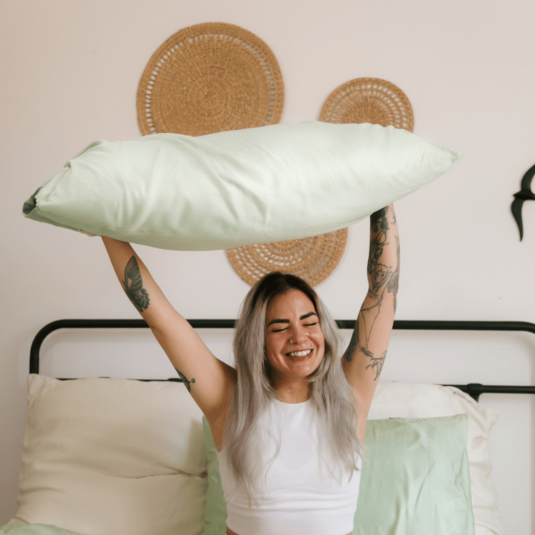 Femme tenant du linge de lit en bambou blanc confortable sur un lit