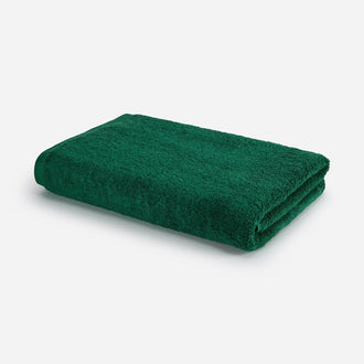 Serviette de bain vert forêt pliée sur fond blanc, design Wabi-sabi par Momo Cotton