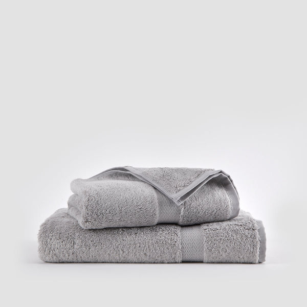 Ensemble de serviettes en bambou gris empilé sur fond blanc montrant serviettes de visage, main et bain