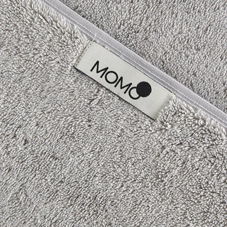 Serviette en bambou gris avec étiquette de marque momo-cotton sur ourlet blanc, gros plan de texture douce