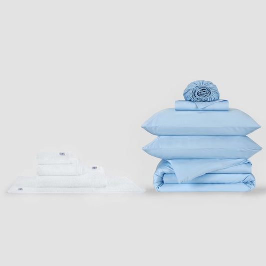 Ensemble de literie bleu et blanc avec oreillers et draps pliés sur fond blanc