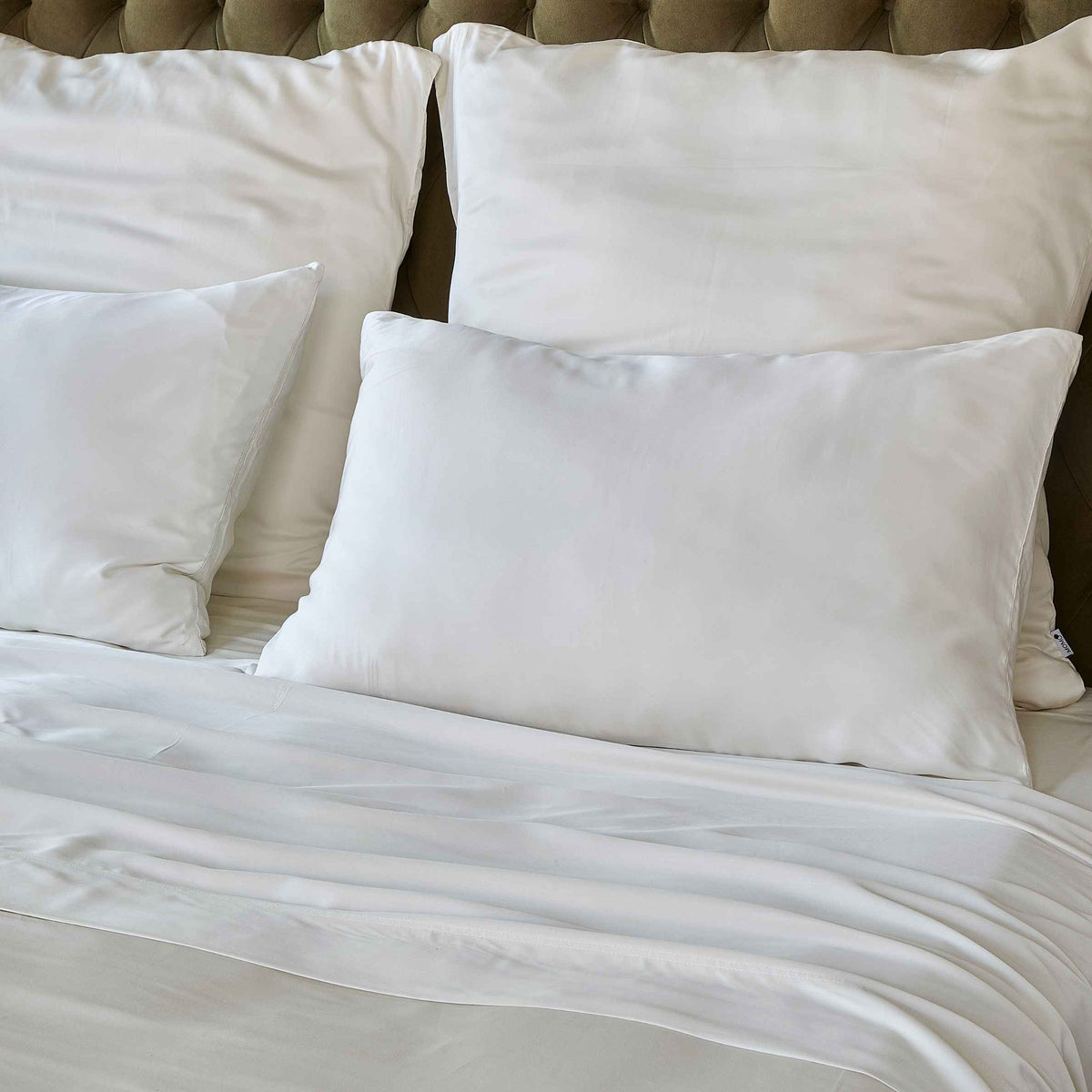 Drap blanc sur lit avec oreillers et tête de lit matelassée beige