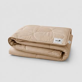 Beige quilted summer bedspread folded with Momo tag visible against white background
