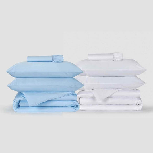 Two duvet cover sets displayed side by side, one light blue and one white, with matching pillowcases and fitted sheets