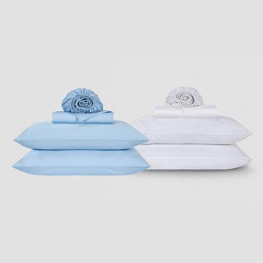 Blue and white cotton sheet sets displayed with pillows and rolled bedding on neutral background