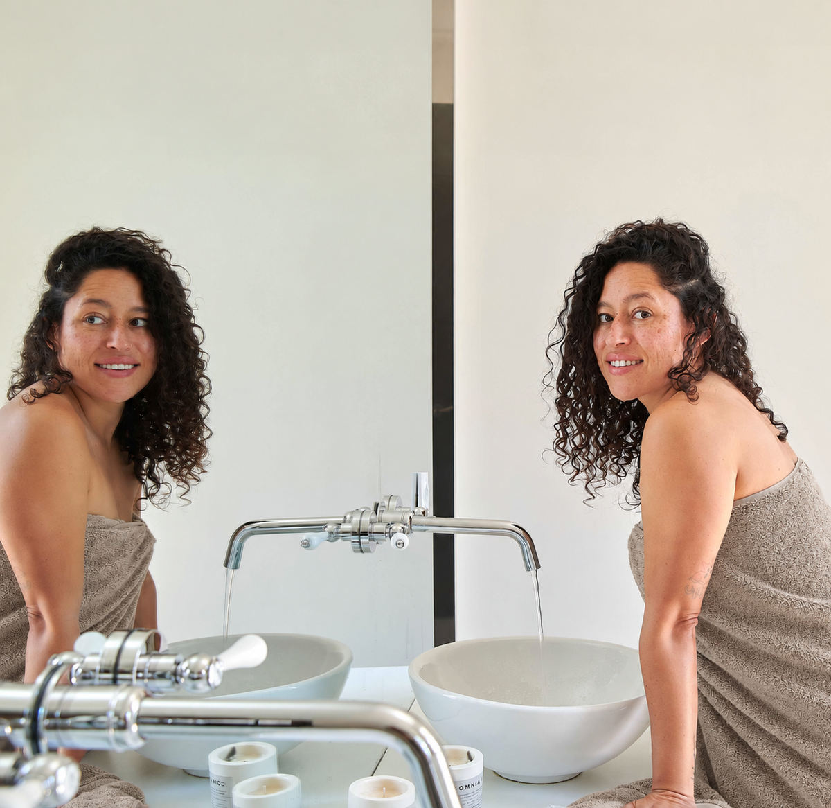 Femme enveloppée dans une serviette en bambou beige devant le miroir de la salle de bain