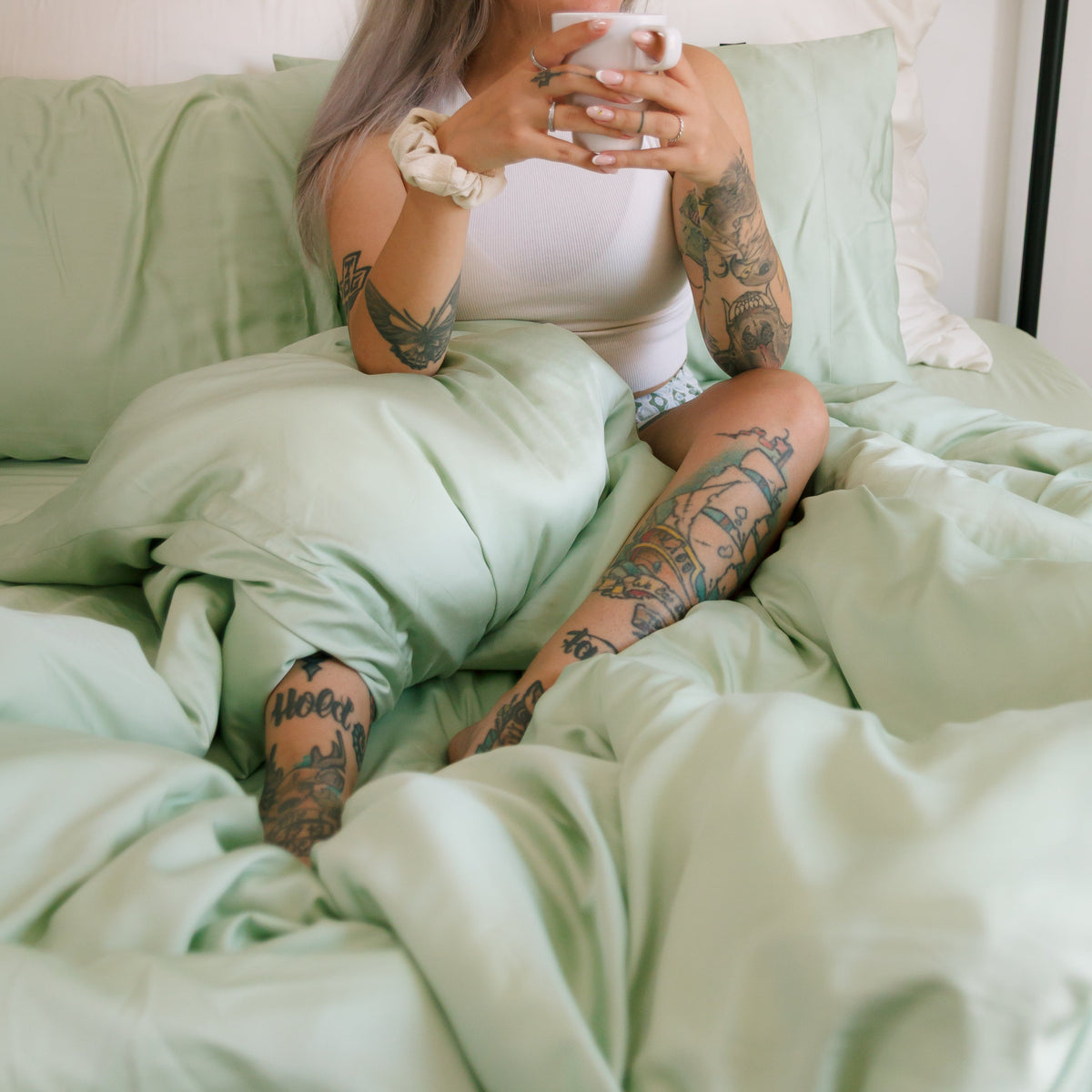 Parure de housse de couette vert menthe sur lit avec linge blanc, mettant en avant la douceur et le confort du tissu
