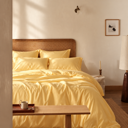 Parure de housse de couette jaune clair sur lit à tête de lit en rotin dans chambre lumineuse