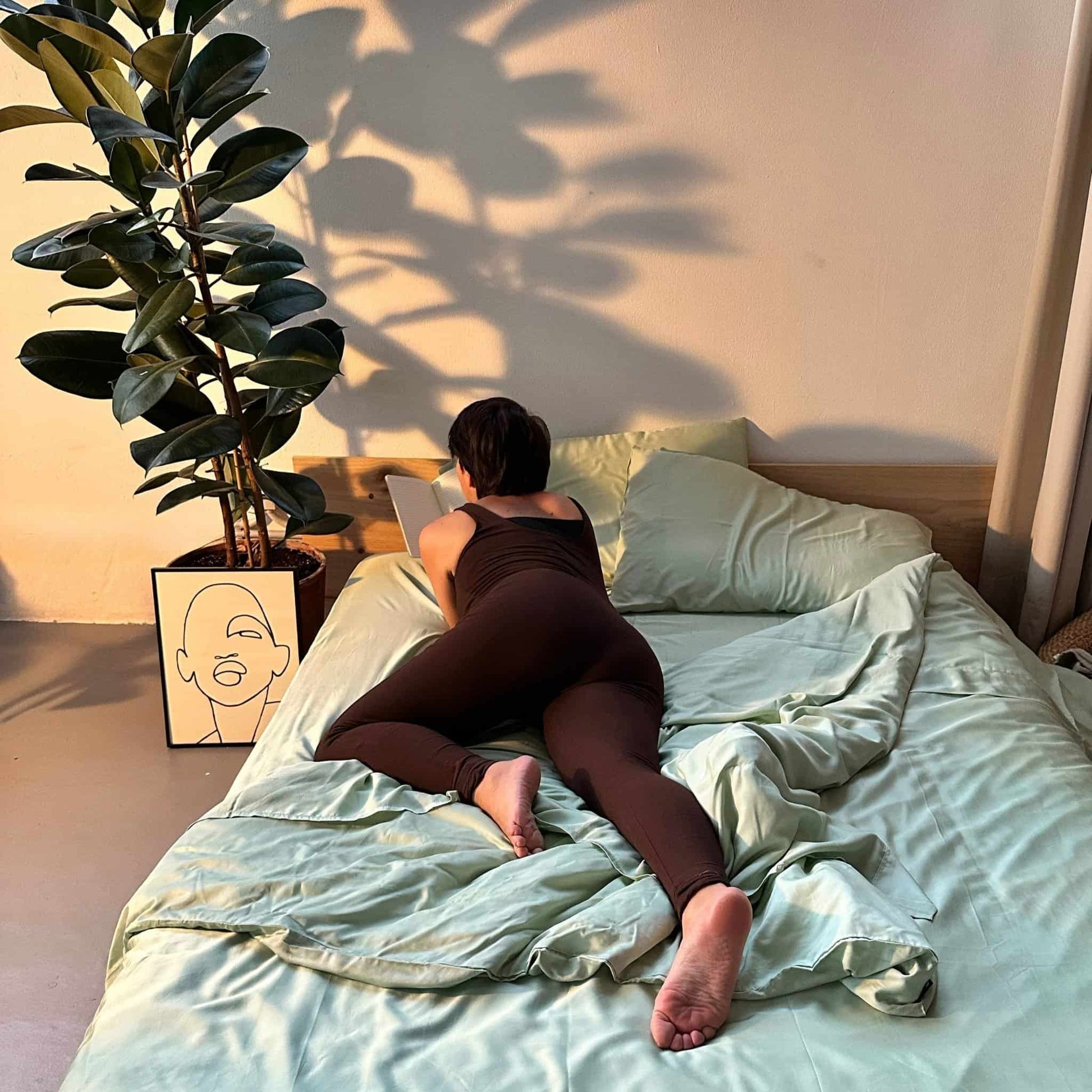 Green bamboo duvet set with woman on bed – duvet and pillows, soft, breathable and sustainable bedding