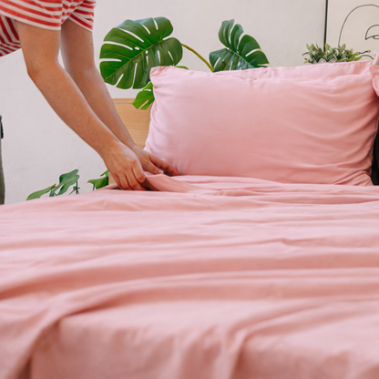 Hands holding pink bamboo fabric, highlighting its lightweight, silky texture.