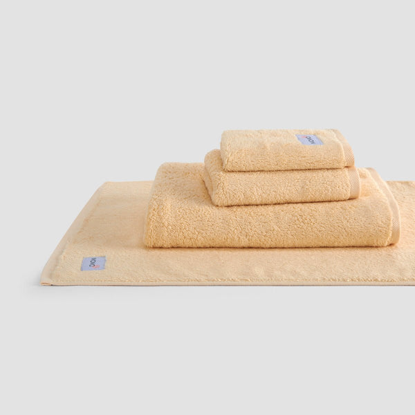 Ensemble de serviettes en bambou beige Wabi-sabi empilées, montrant serviettes de visage, main et bain